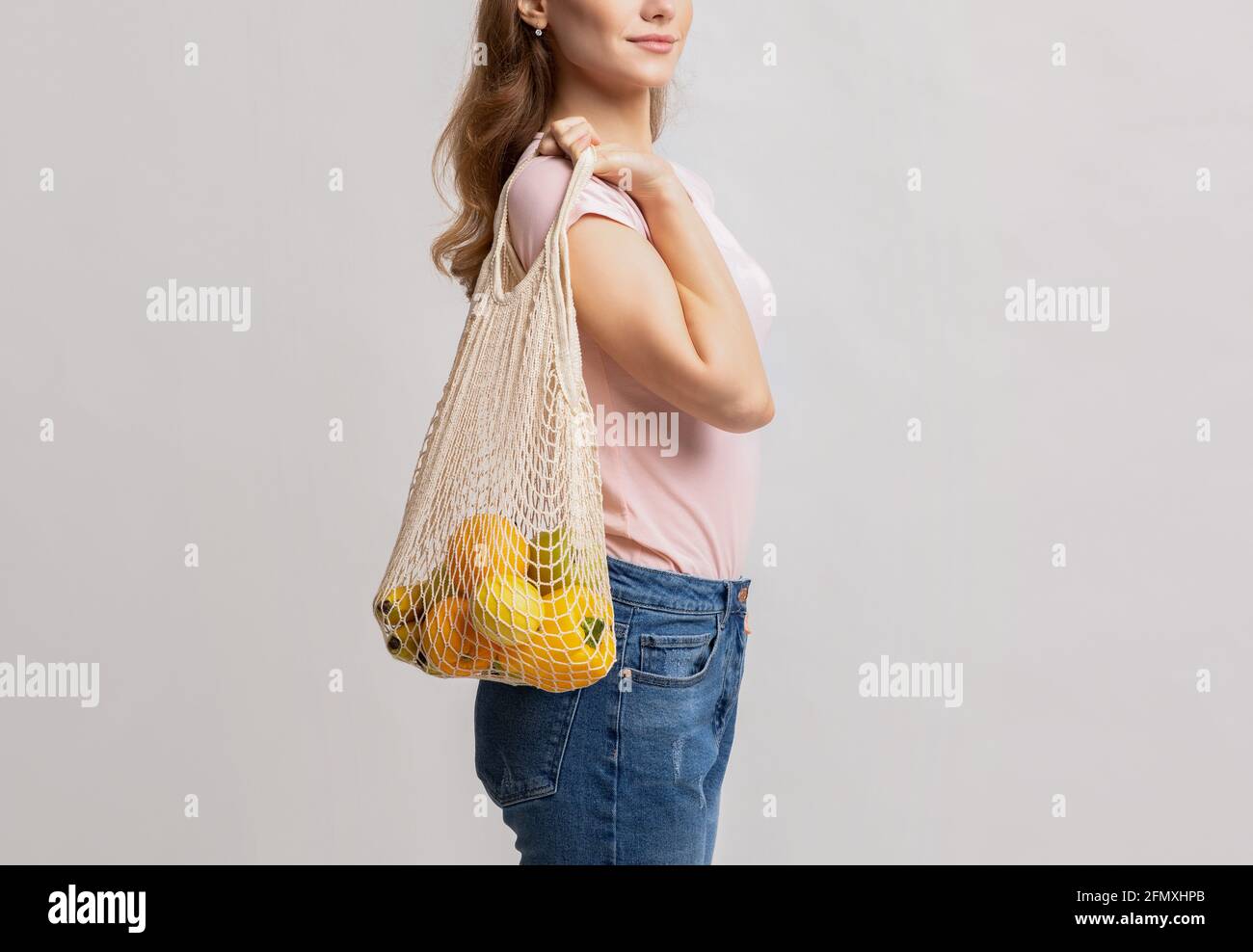 Vita ecologica. Millennial Femminile che trasporta verdure e frutta in sacchetto riutilizzabile di maglia Foto Stock