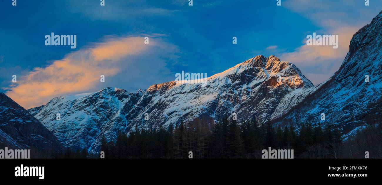 Vista panoramica con la luce dell'ora d'oro e il cielo colorato in una serata invernale nella valle di Romsdalen, Rauma kommune, Møre og Romsdal, Norvegia. Foto Stock
