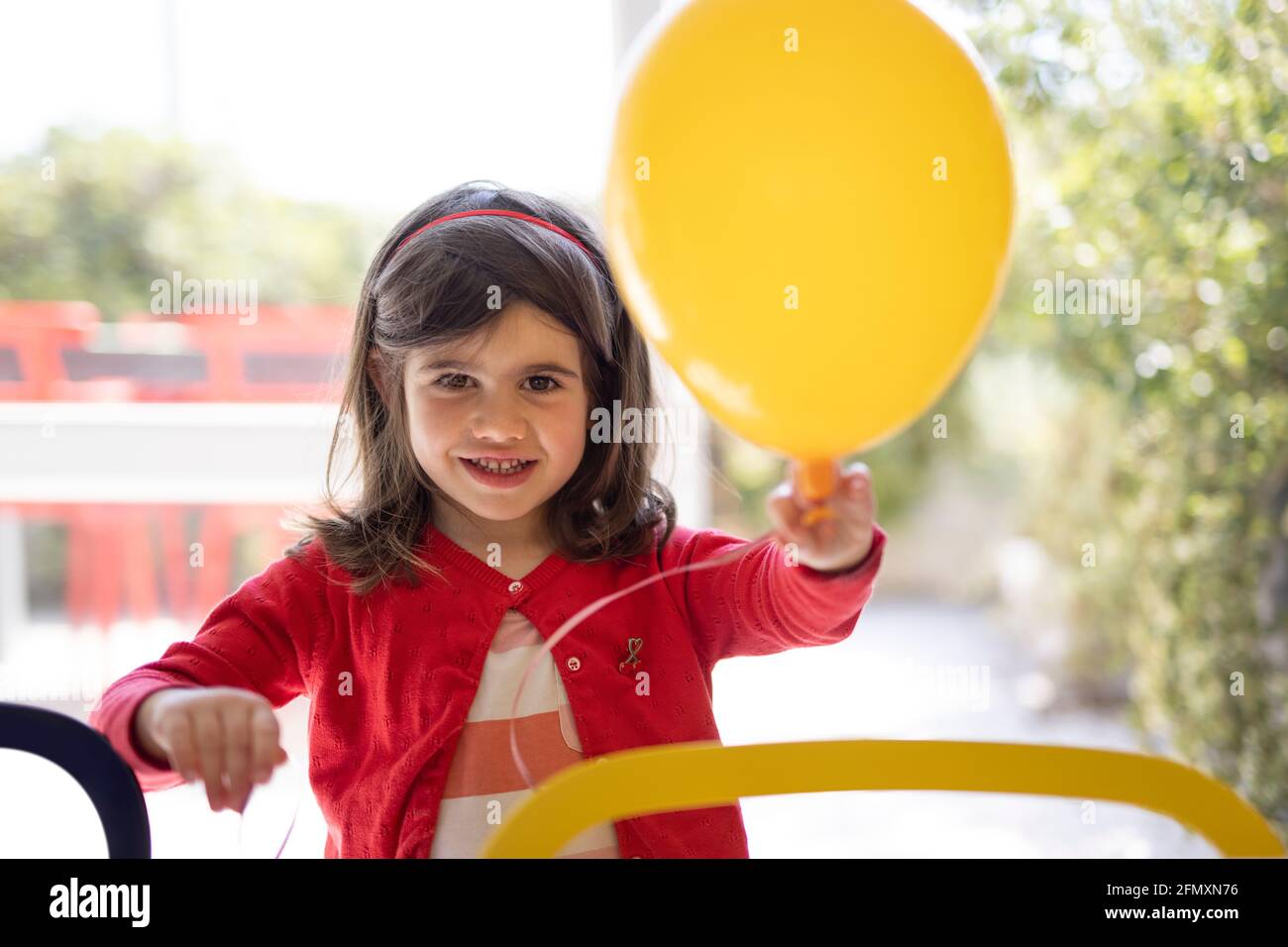 Ritratto di una bambina di quattro anni che tiene in mano un pallone. Bambina che si diverte con un pallone. Foto Stock