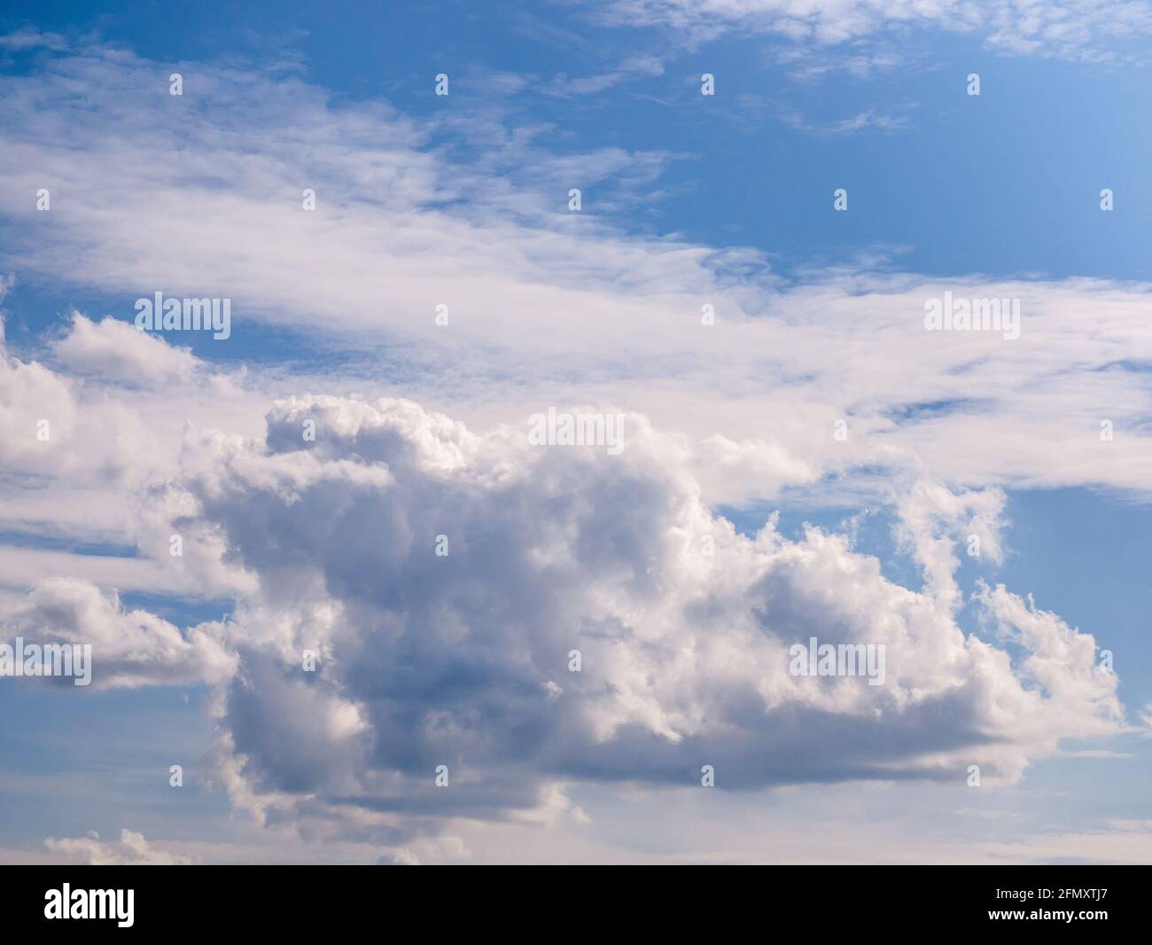 Una bella nuvola lacerata dal vento perde lentamente la sua forma al bordi nel cielo blu Foto Stock