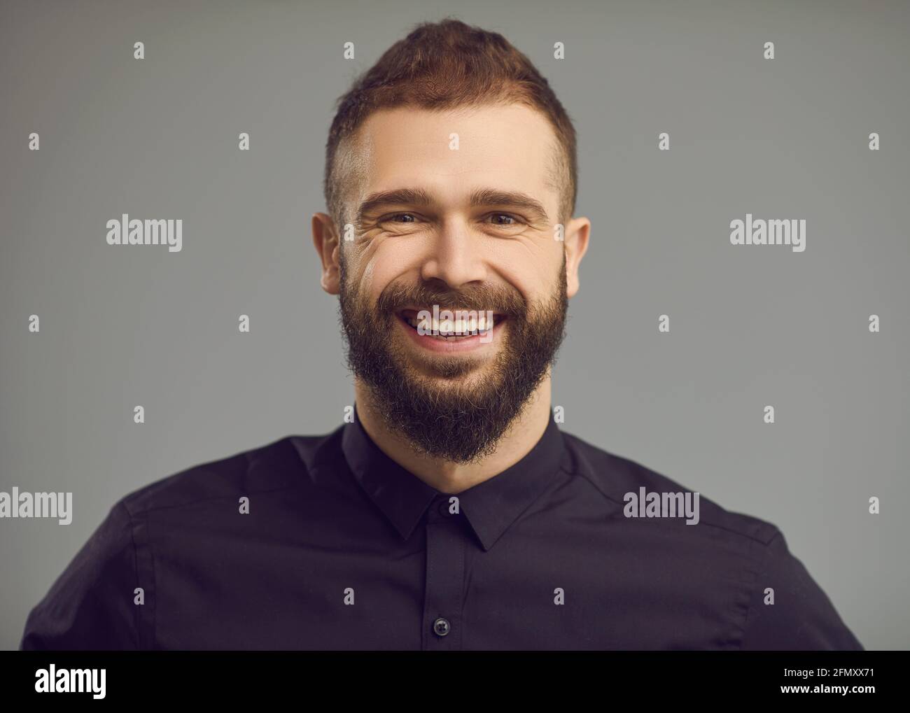 Studio ritratto di giovane elegante bearded con sorriso felice sul suo volto amichevole Foto Stock