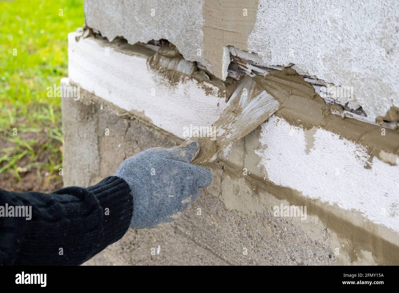 Lavori di muratura. Mano da lavoro in guanto blu con cazzuola. Foto Stock