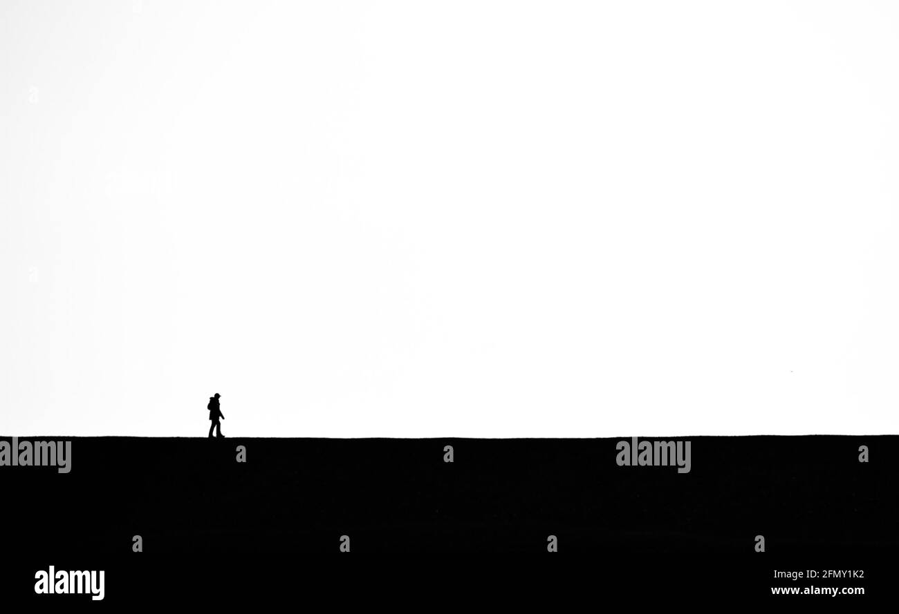 Bianco e nero, monocromo di una persona sola camminando sull'orizzonte Skyline stile minimalista UK Foto Stock