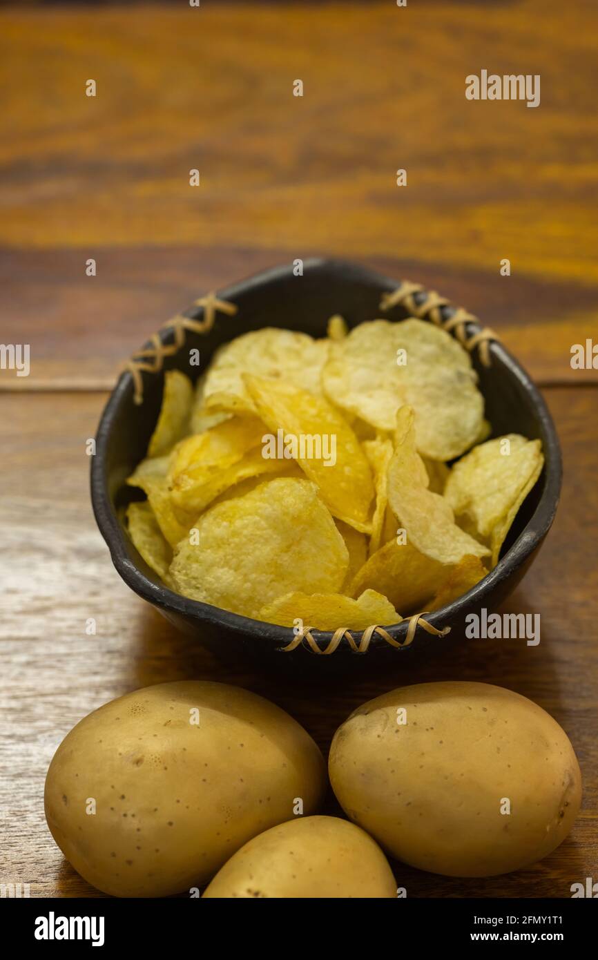 Patate crude e una ciotola piena di fritti dorati freschi patatine croccanti Foto Stock