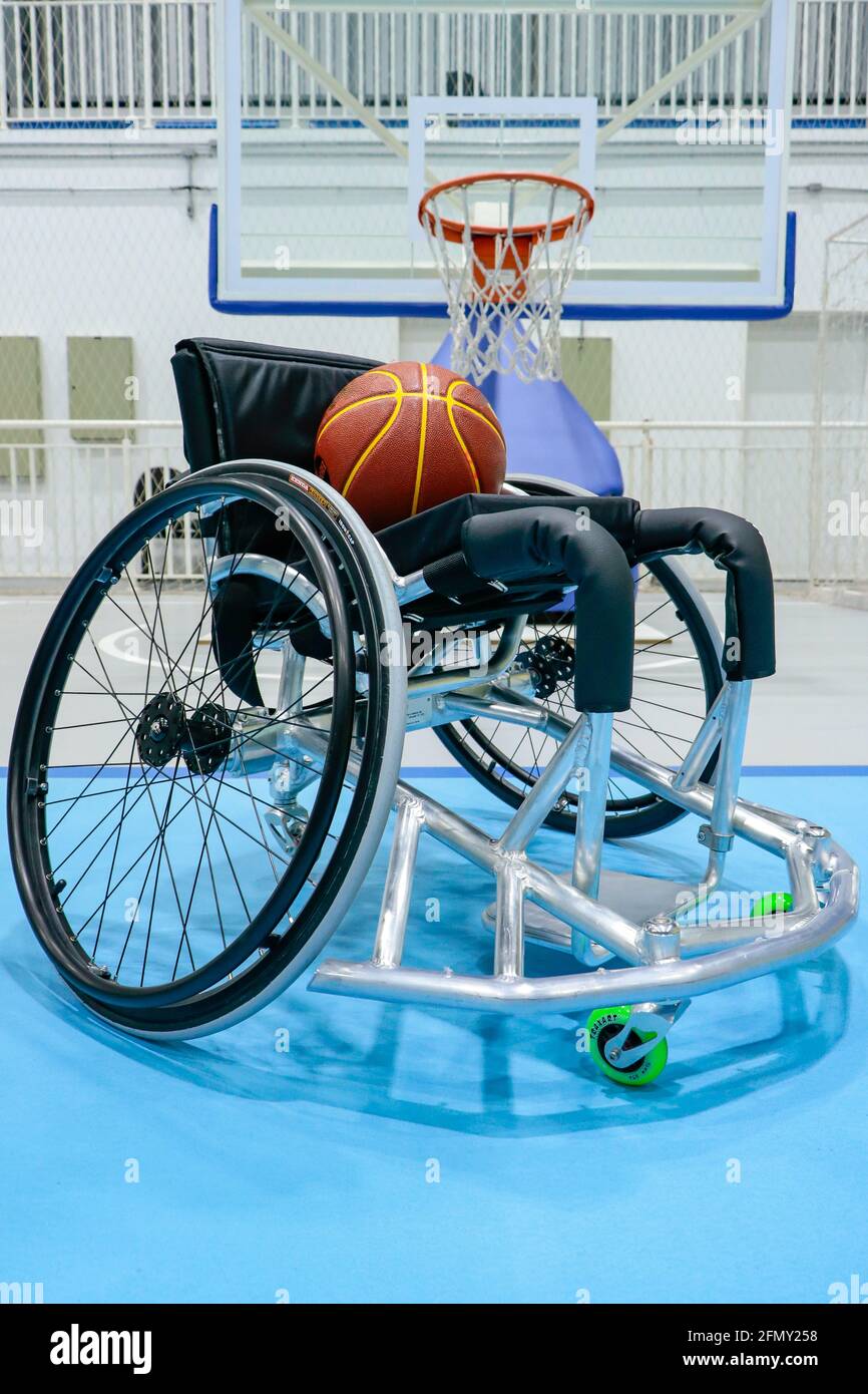 Sedia a rotelle per i giocatori di basket paralimpici, con una palla da  gioco sulla sedia e in basso il tavolo con il canestro da basket Foto stock  - Alamy
