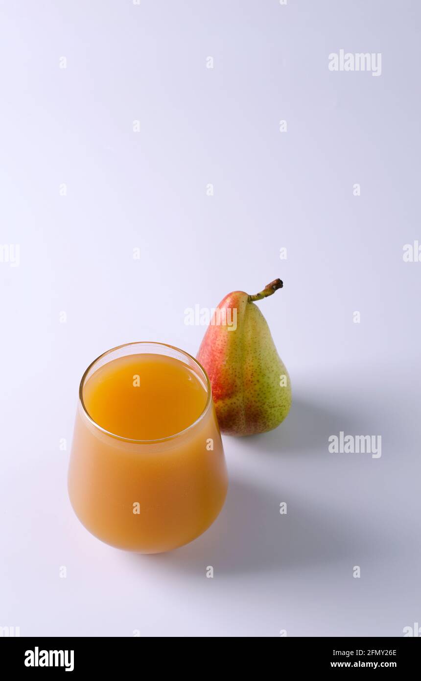 Succo di frutta con polpa in vetro trasparente e pera su sfondo chiaro. Il concetto di cibo sano e bevande, spazio di riproduzione, foc selettivo Foto Stock