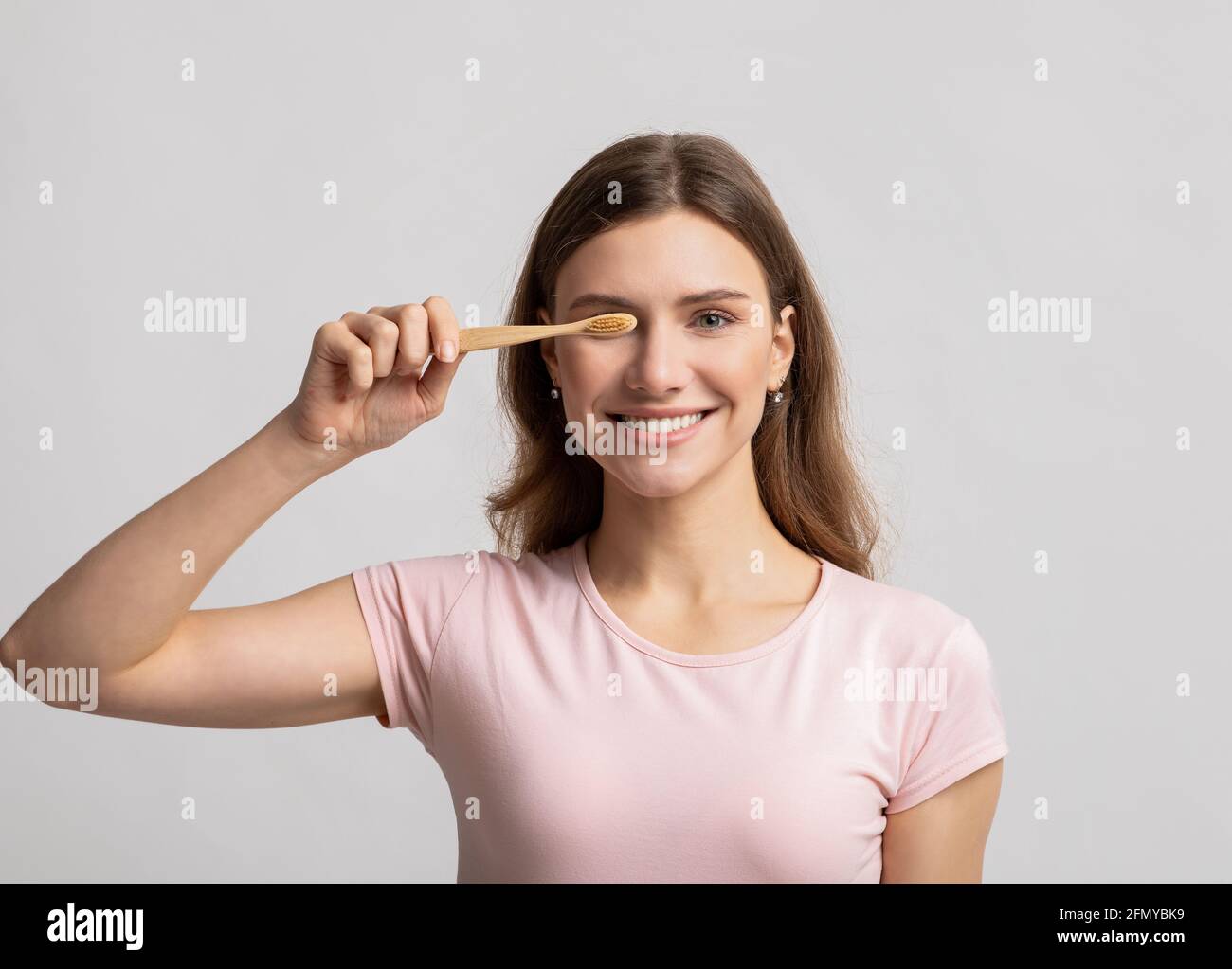 Concetto di Eco Living. Felice bella giovane donna che tiene lo spazzolino naturale di bambù di legno Foto Stock