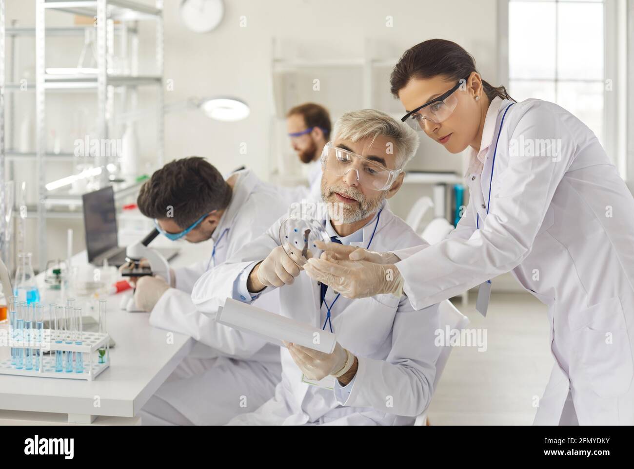 Supervisore senior e assistente studente che discutono di un campione di test in ambito scientifico laboratorio Foto Stock