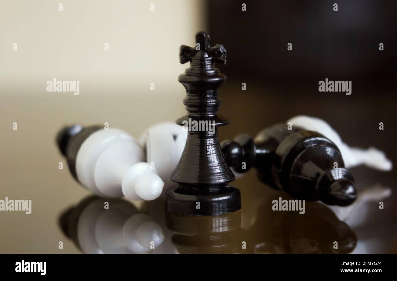 Scacchi neri tra pegni di icona caduti come nemici. Vincitore e perdenti. Concetto con pezzi a scacchi su sfondo bianco e nero, Closeup Foto Stock