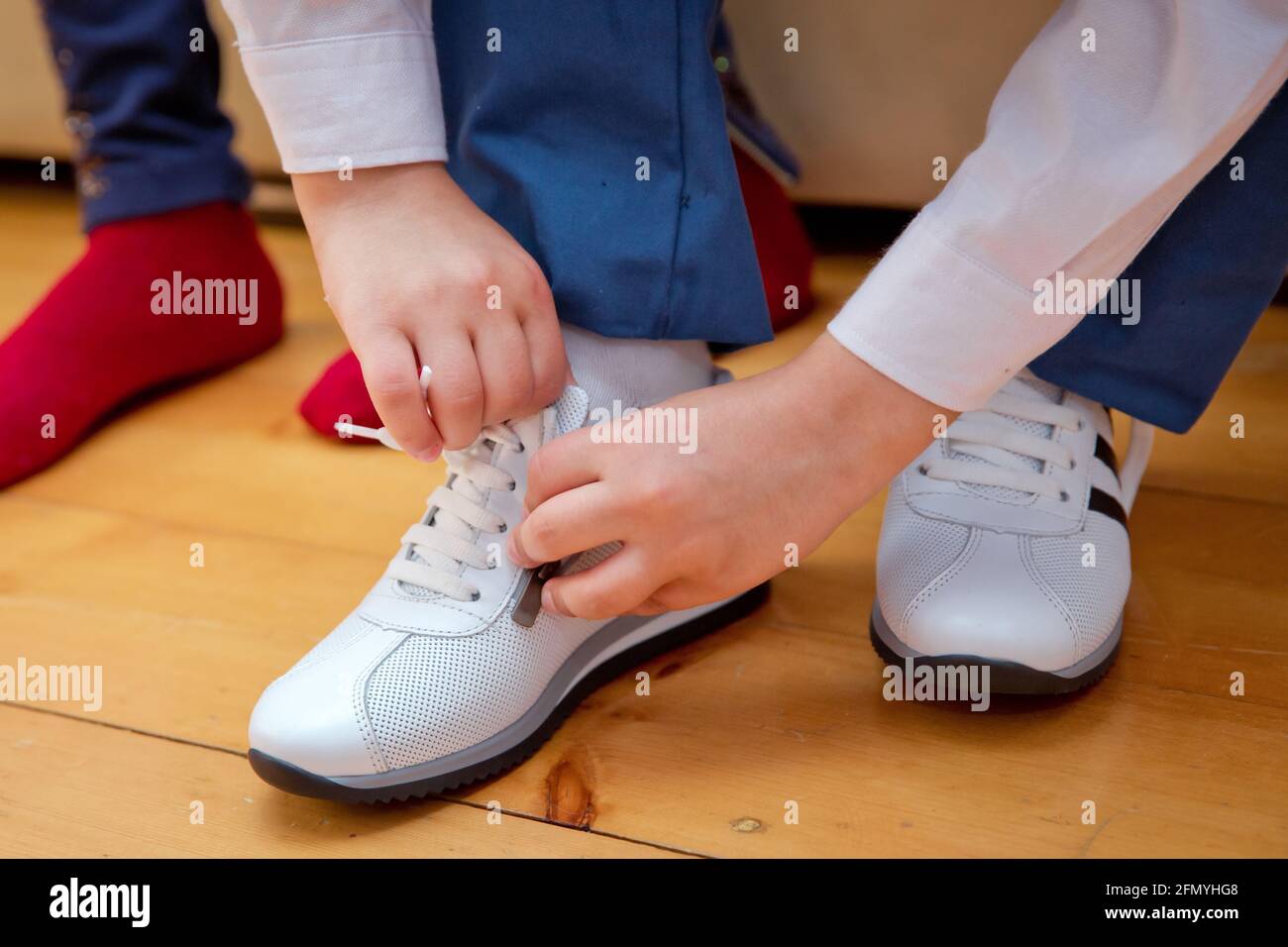 Il bambino indossa un paio di sneakers. Le gambe del ragazzo in sneakers bianco di moda. Abbigliamento casual alla moda per bambini e moda di strada. Primo piano Chiude il Foto