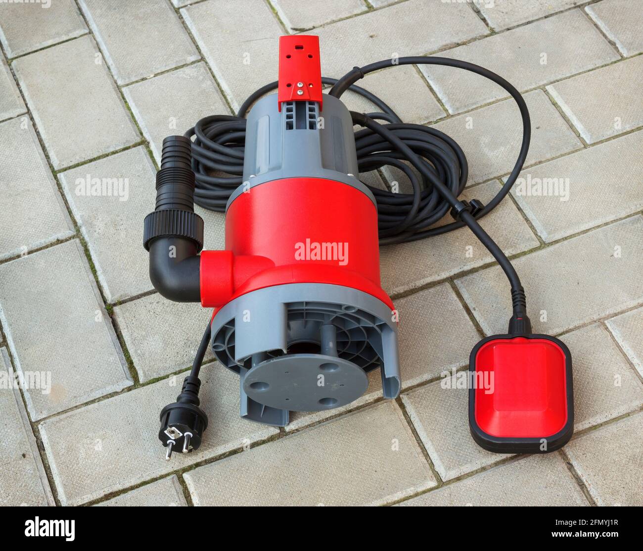 La pompa sommersa per uso domestico con alloggiamento in plastica si trova sul pavimento in pietra di cortile Foto Stock