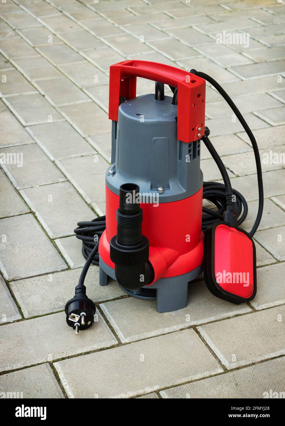 Pompa sommersa per uso domestico con alloggiamento in plastica sul pavimento in pietra di cortile Foto Stock