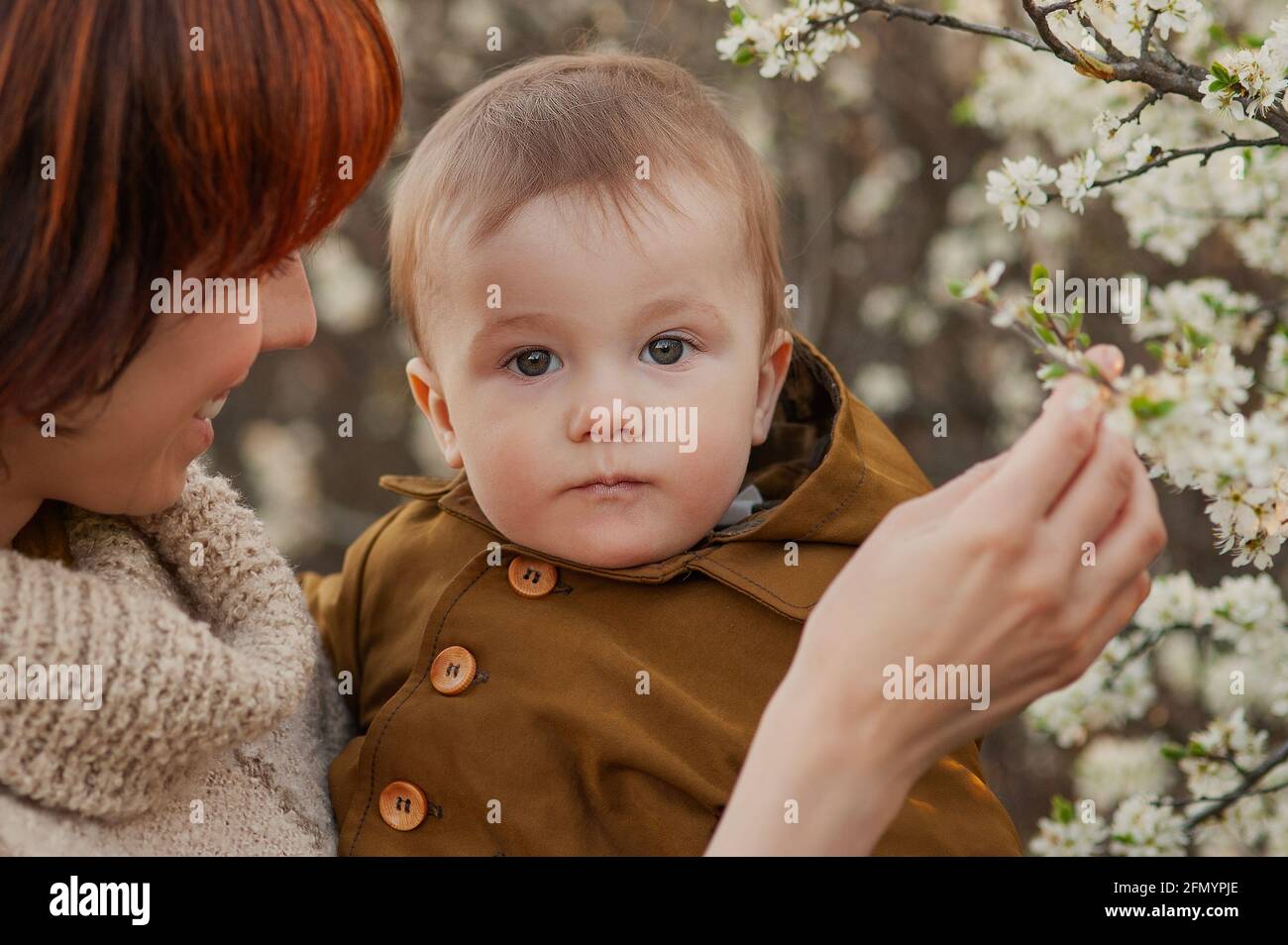 La mamma tiene il bambino sullo sfondo di alberi in fiore Foto Stock