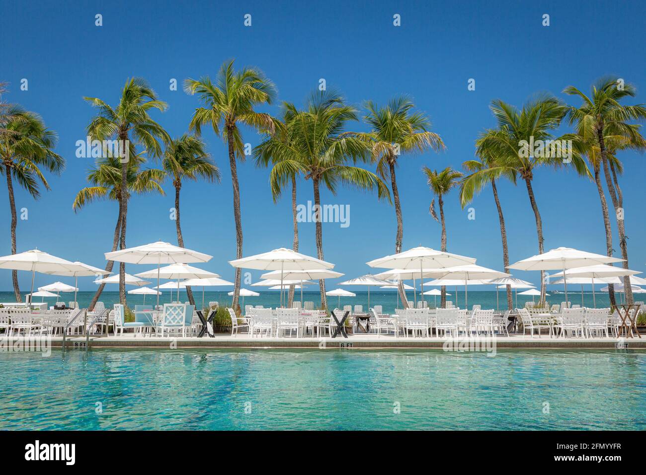 Tavoli e ombrelloni allestiti intorno alla piscina con vista sul Golfo del Messico a Napoli, Florida, USA Foto Stock