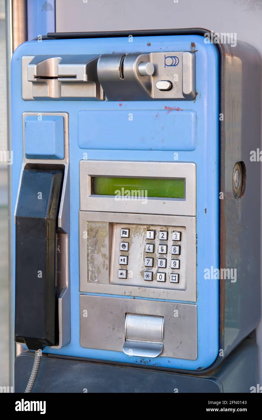 una vecchia cabina telefonica blu danneggiata e fuori servizio con segni di deterioramento e qualche bendatura dipinta su di essa, verticale Foto Stock
