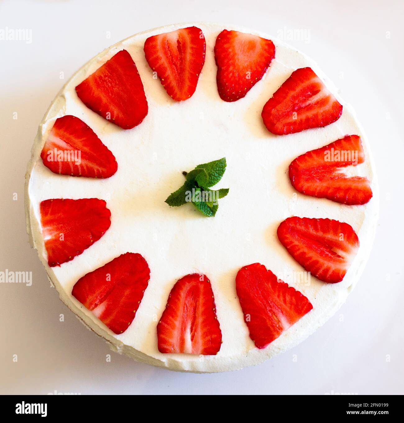 Composizione top-down di torta fatta in casa di fragola e crema con foglie di menta sulla parte superiore. Foto Stock