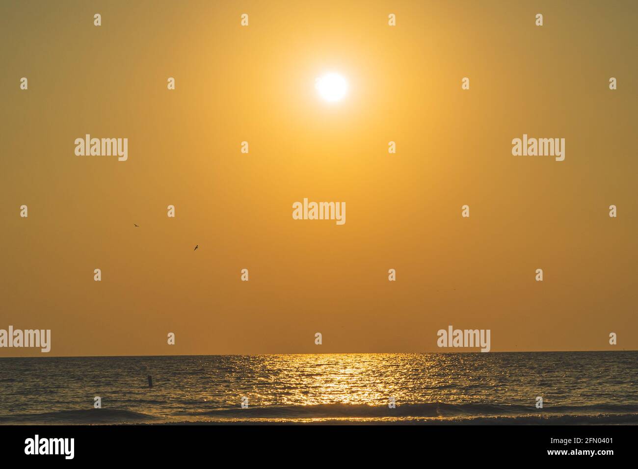 Vista panoramica del sole nel cielo arancione che si riflette sul acqua durante il tramonto Foto Stock
