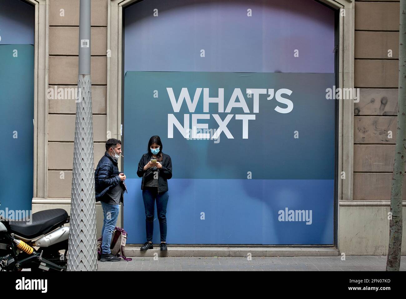 Una coppia in piedi accanto a un poster che recita " What's next ", Barcellona, Spagna. Foto Stock