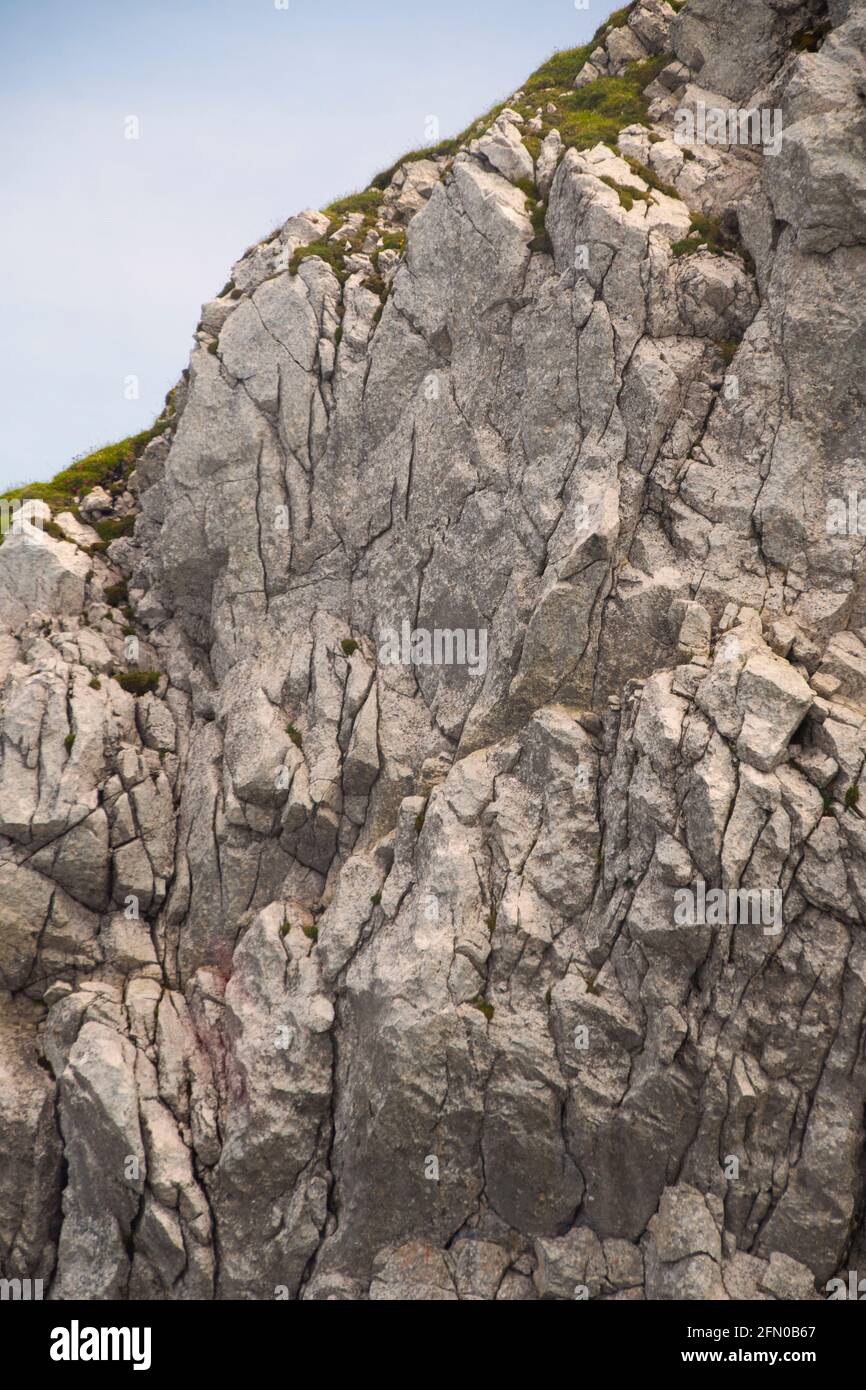 Un cielo blu e terra erbosa sul bordo della montagna. Con strati rocciosi. Foto Stock