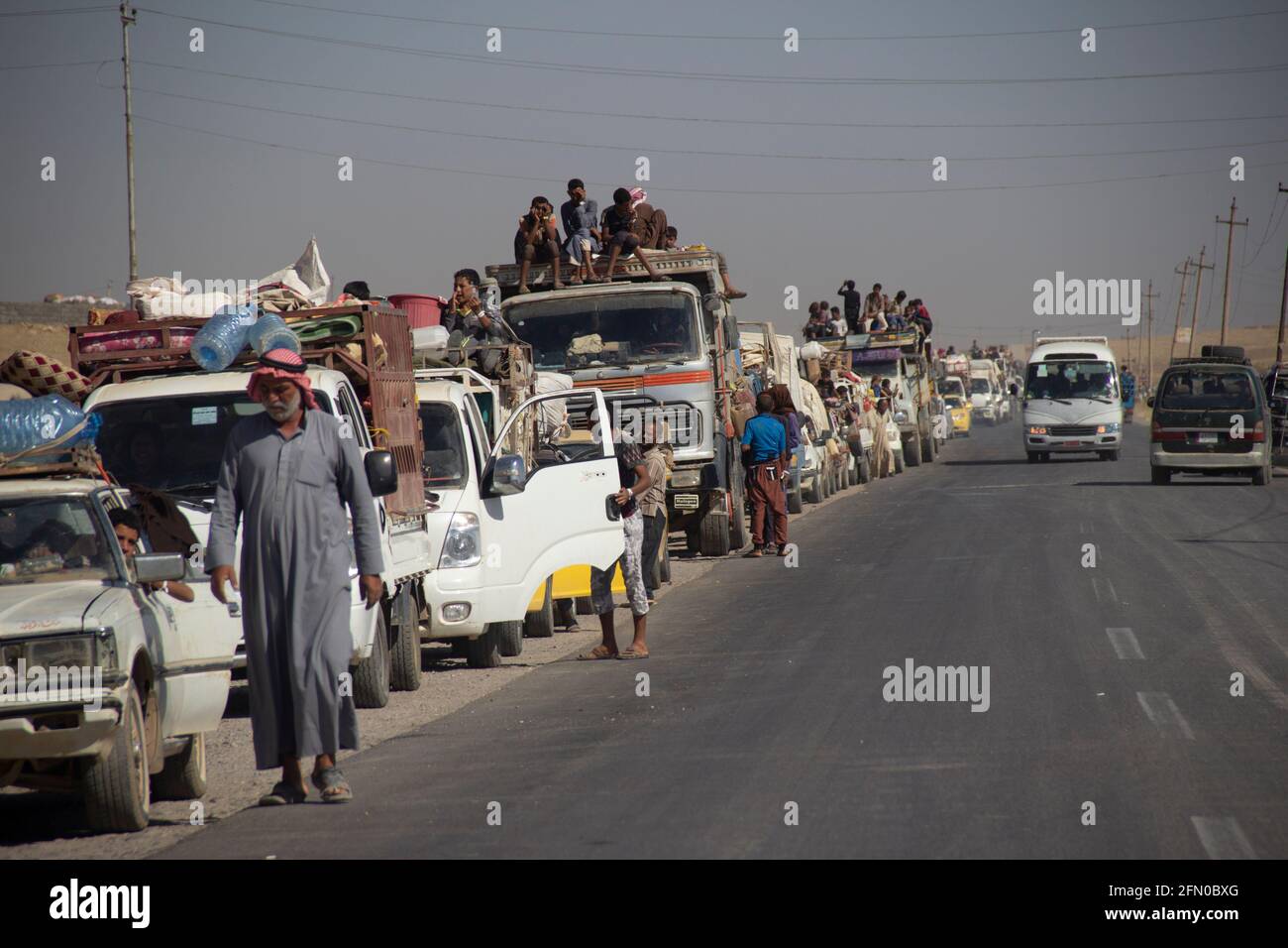 Mosul, Iraq. 9 giugno 2017 UNA lunga linea di vetture attende lungo la strada che porta fuori Mosul. Foto Stock