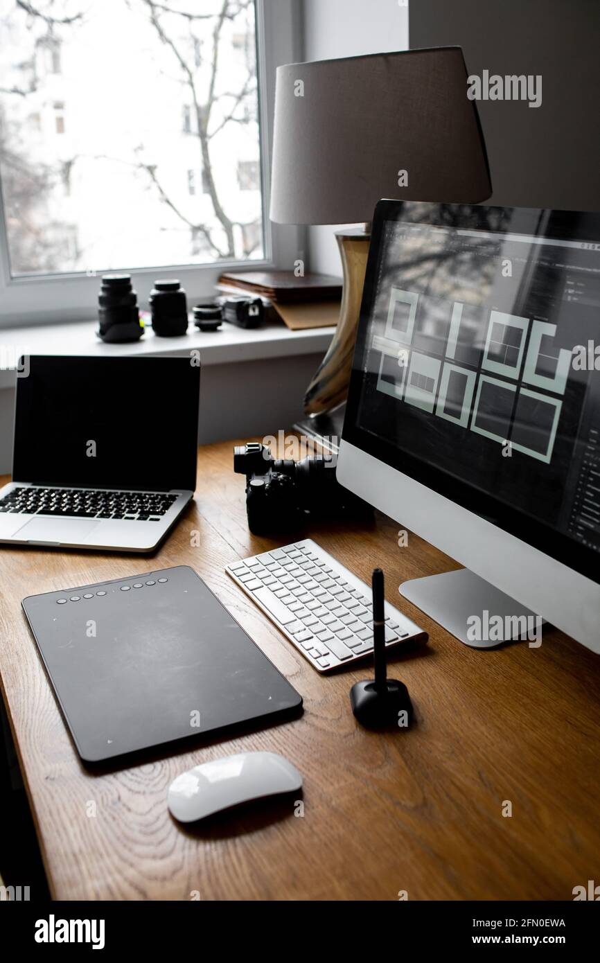 Spazio di lavoro elegante con computer portatile a casa o in studio. Luogo di lavoro del fotografo Foto Stock