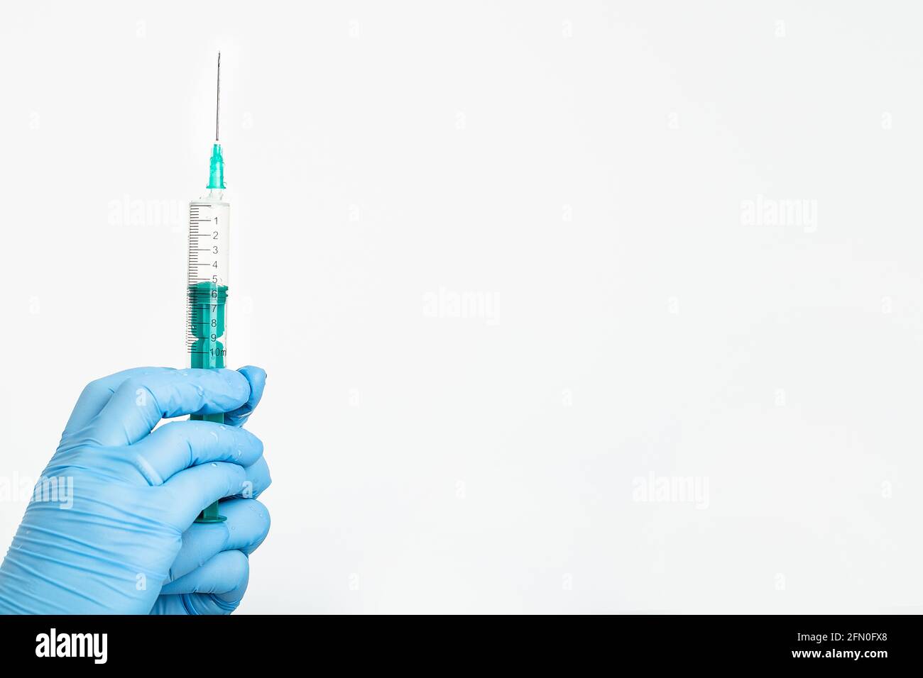 Una mano del medico in un guanto medico contiene una siringa con un ago per proteggere contro il virus dell'influenza. Vaccino CVD. Il concetto di vaccinazione medica Foto Stock