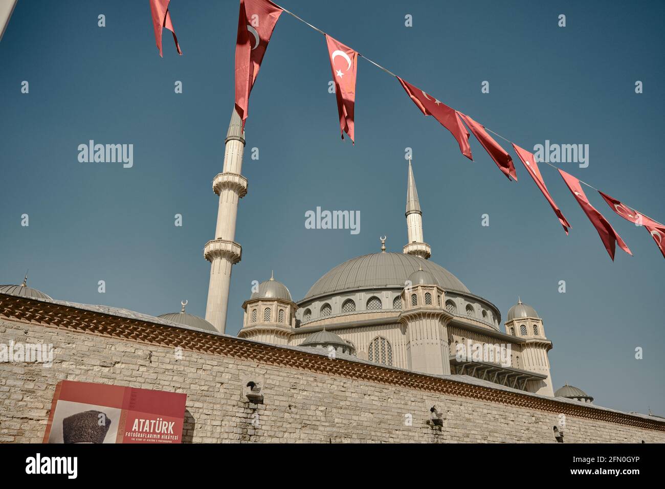 Piazza Taksim coperta da molte bandiere turche e moschea taksim quasi finito. Poster Ataturk e il suo nome in foto con moschea e minareto di recente estab Foto Stock