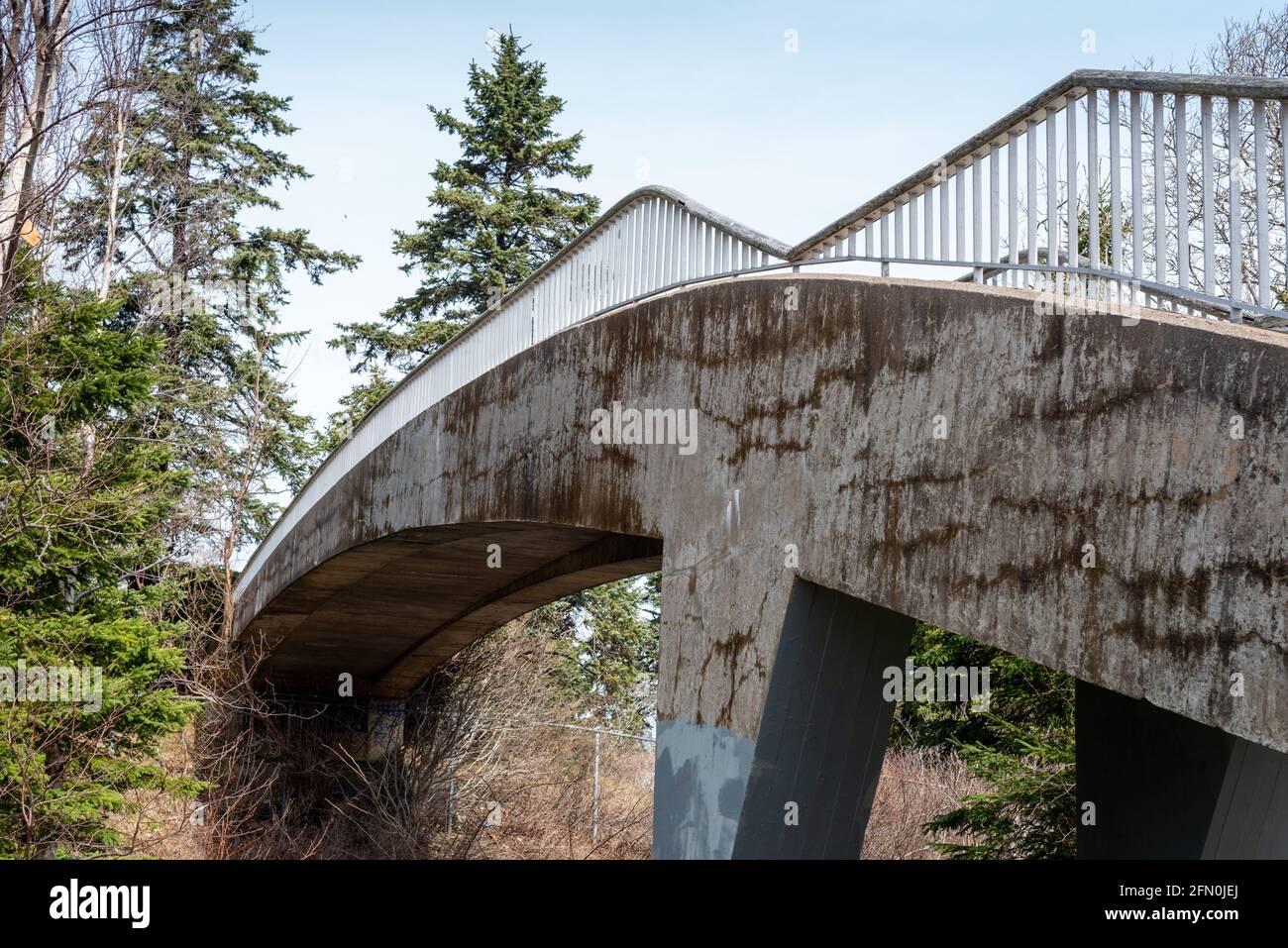 Un ponte a sbalzo su un sentiero in cemento d'epoca che si estende su un sentiero in un parco. Foto Stock