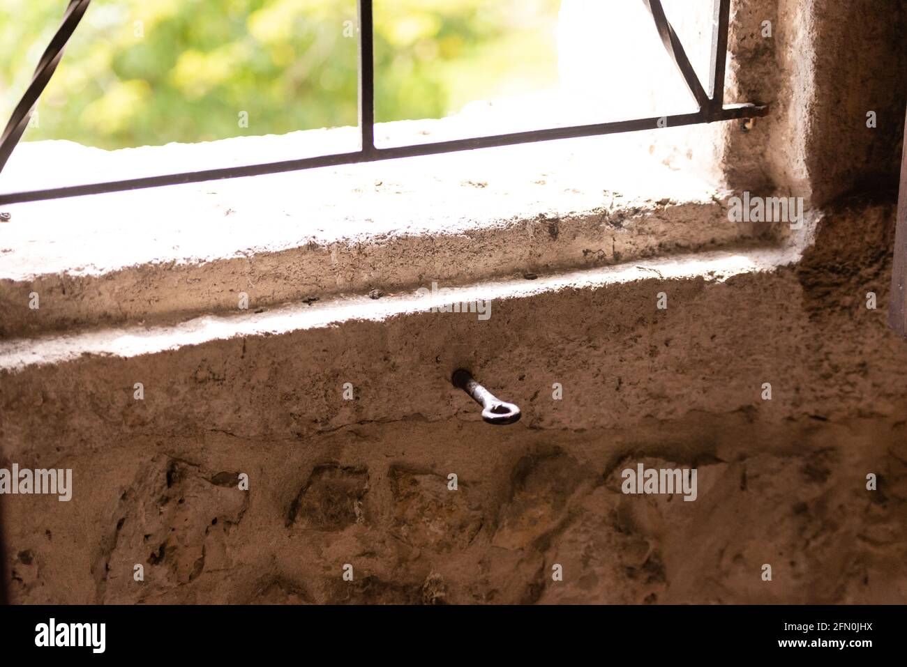 Un gancio martellato con un anello sotto il vetro. Vecchia finestra senza vetro con barre. Foto Stock