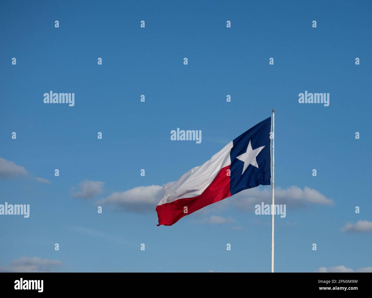 Bandiera dello stato Texas Lone Star con stella bianca su sfondo blu svanita in una giornata ventosa. Cielo blu con nuvole sullo sfondo. L'immagine ha spazio per la copia. Foto Stock