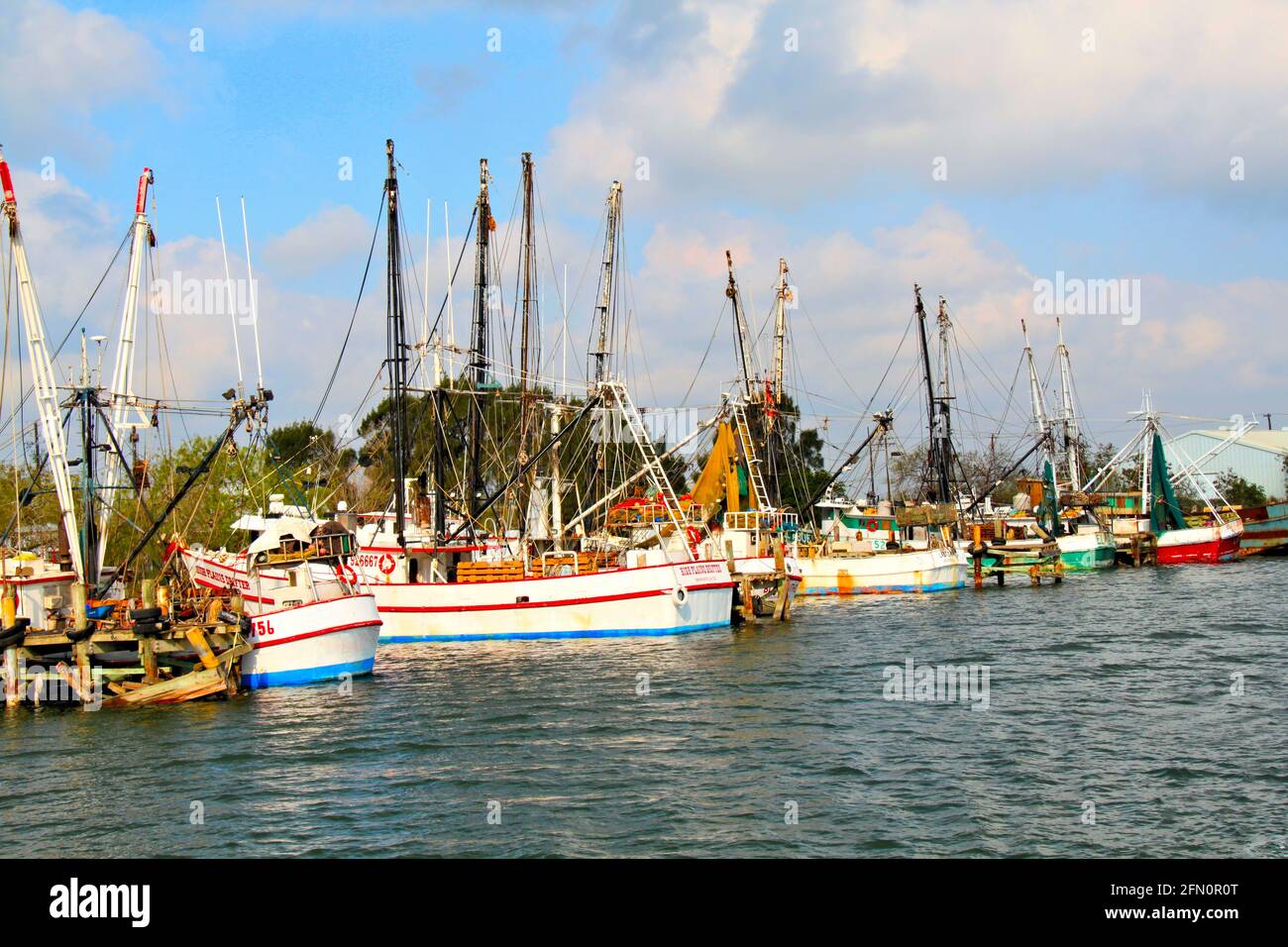 Un gruppo di barche di gamberi attraccati vicino a Brownsville, Texas, U.S.A. In una giornata soleggiata con un cielo blu e nuvole bianche. Foto Stock