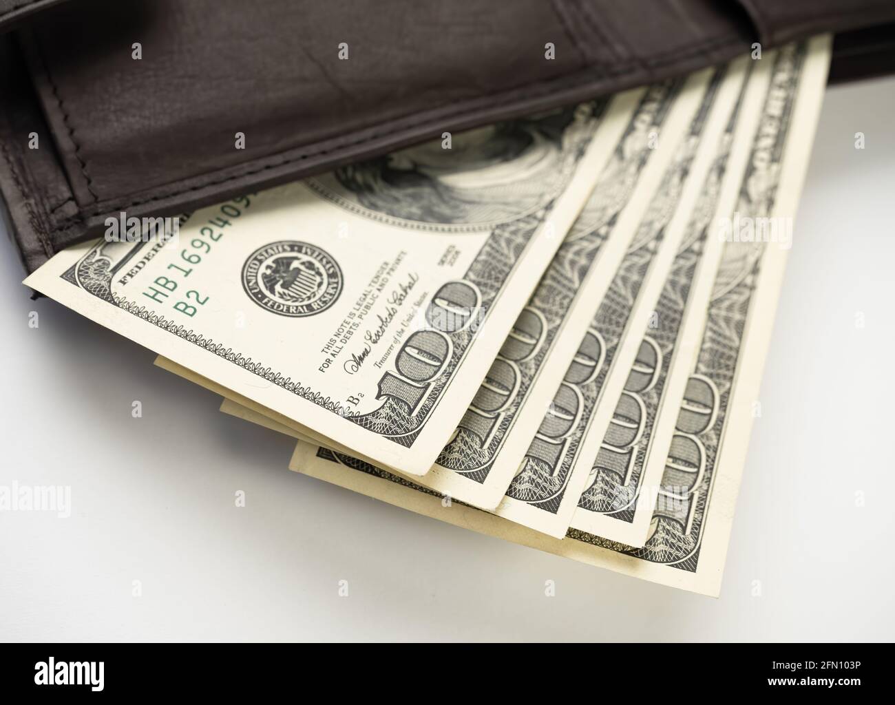Portafoglio in pelle pieno di denaro su sfondo bianco - fan di cento banconote USA con ritratto del presidente Franklin. Contanti di cento dollari fatture, Pap Foto Stock