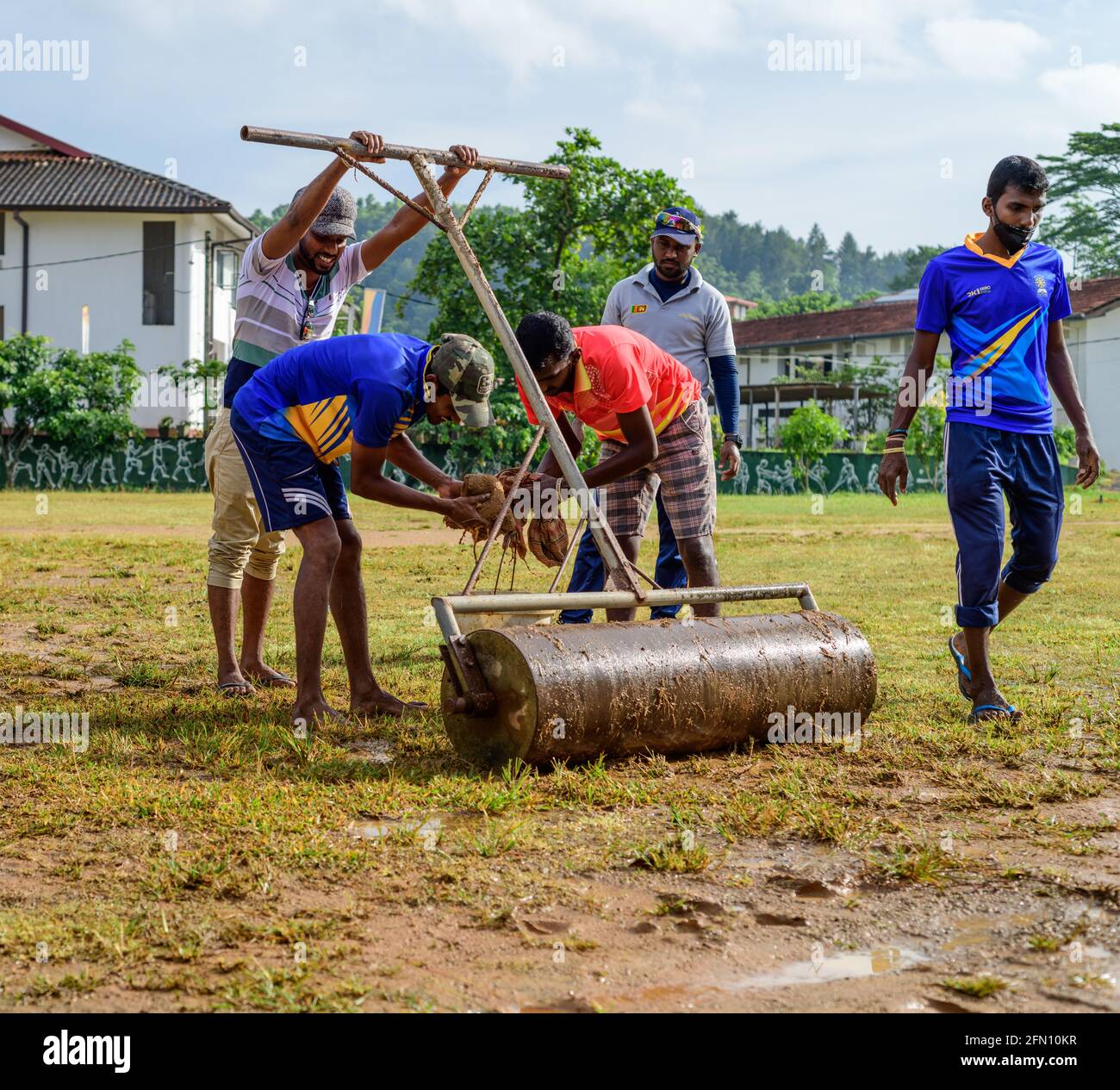 Galle, Sri Lanka - 04 17 2021: Giocatori e staff preparano il campo di cricket e il terreno dopo la pioggia pesante. Rimozione di acqua in eccesso e fango mentre rullo u Foto Stock