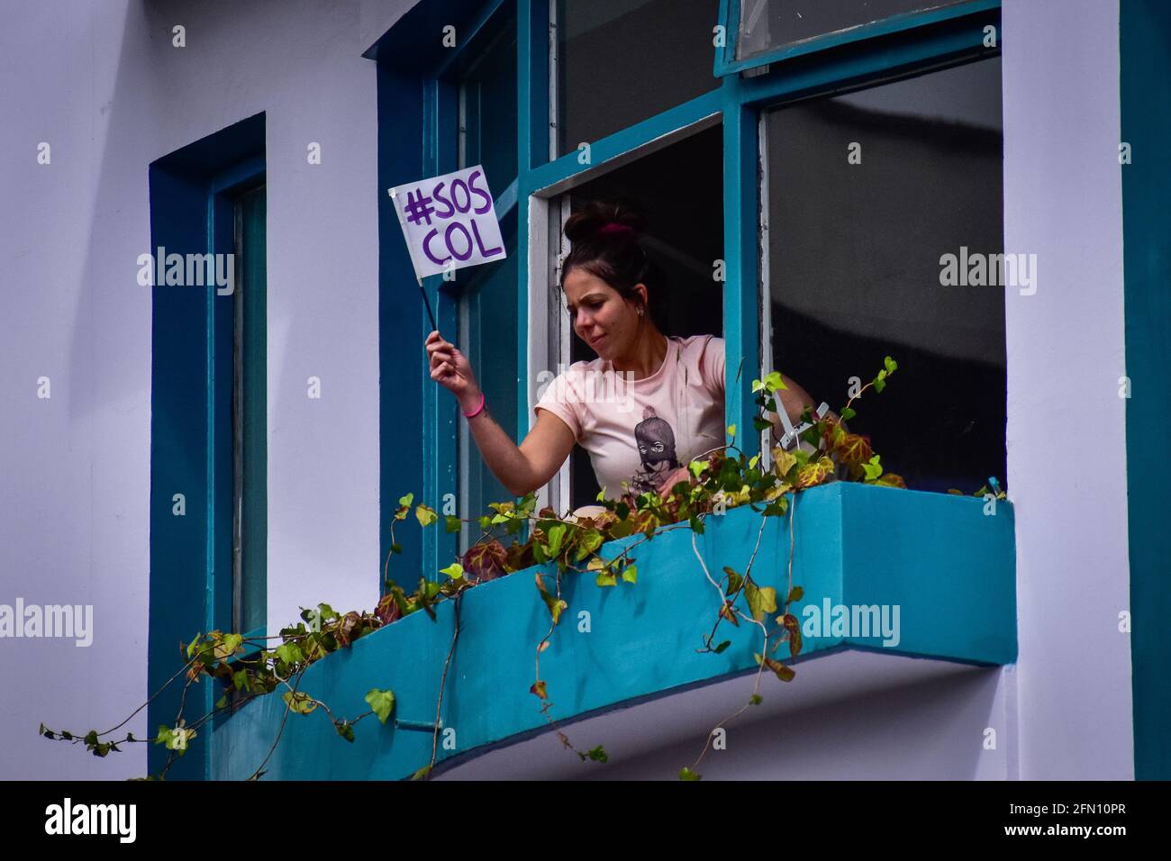 Passo, Narino, Colombia. 12 maggio 2021. Donna sbirciata fuori dalla sua finestra con un segno che dice: 'S.O.S. COLa'' che fa riferimento alla situazione critica del paese a Pato; Narino, Colombia il 12 maggio 2021 Credit: Camilo Erasso/LongVisual/ZUMA Wire/Alamy Live News Foto Stock