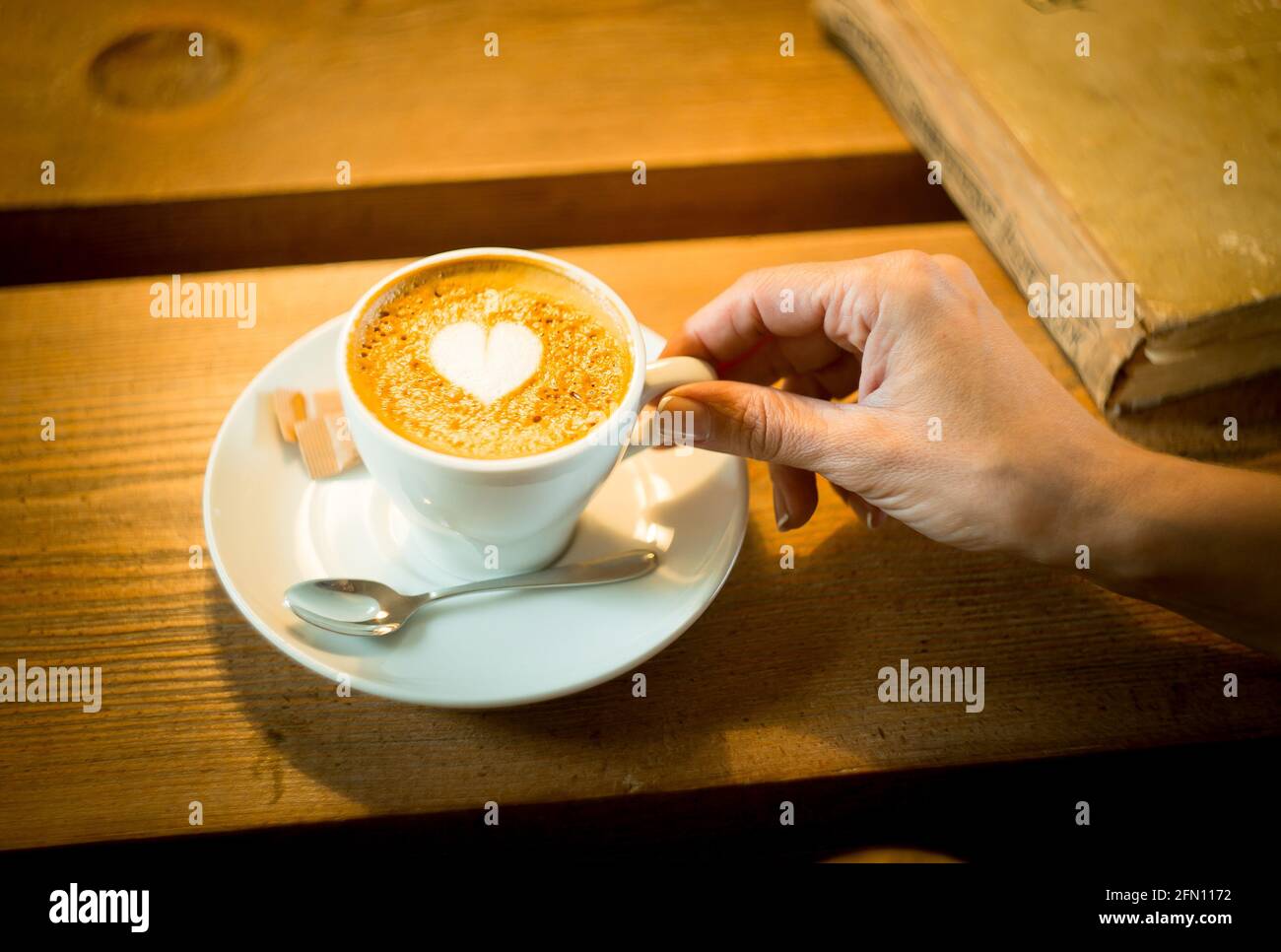 Storie d'amore. Tazza con caffè su un tavolo di legno. C'è un cuore sulla superficie. Foto Stock