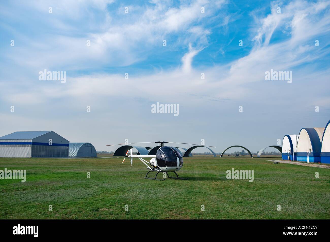 Elicottero bianco ultraleggero su campo di volo verde nell'aeroclub Foto Stock