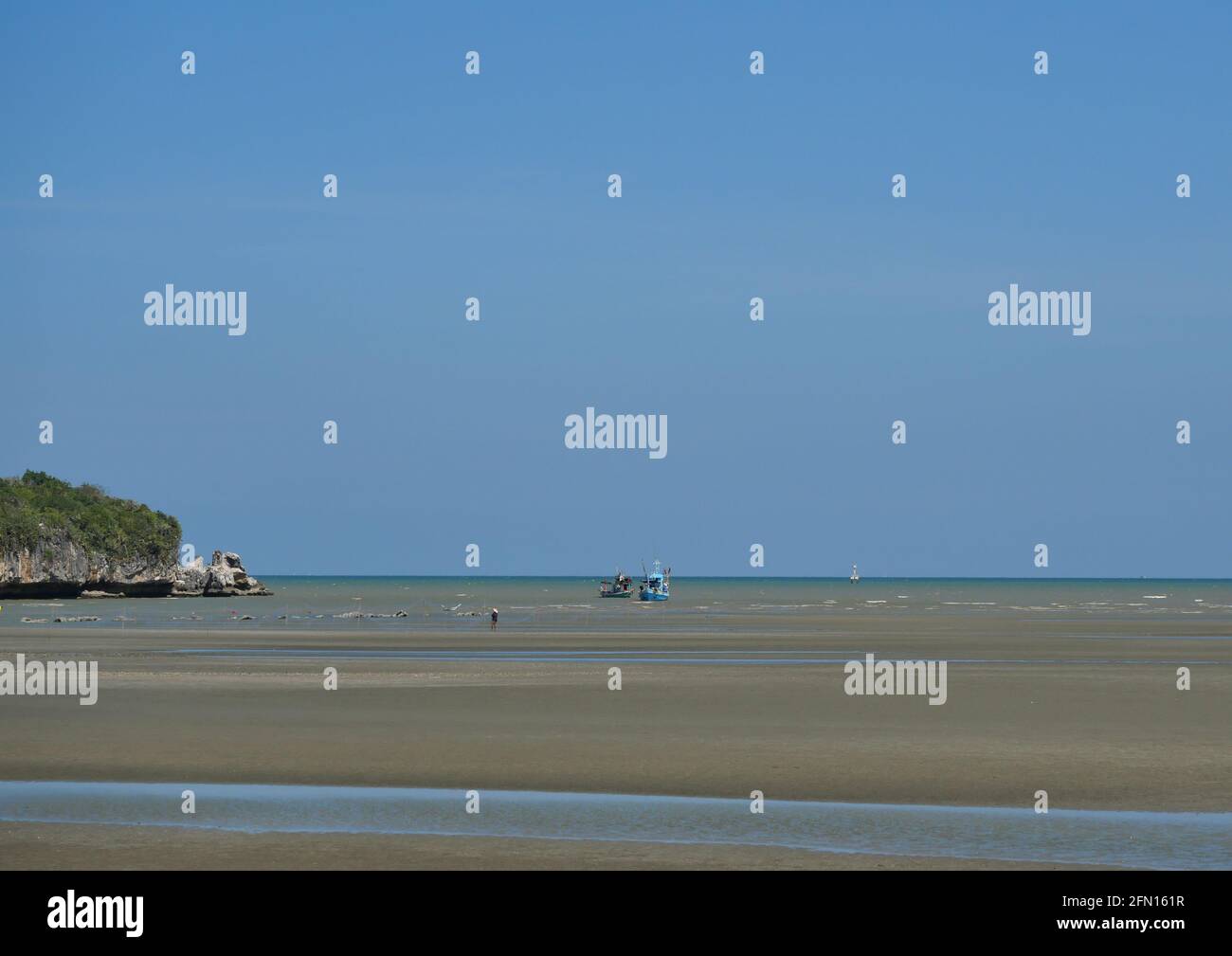 Montagna con sabbia e fango in acqua fenomeno a bassa marea, pesca barca sulla spiaggia, le onde oceaniche splash la riva severamente, Thailandia Foto Stock