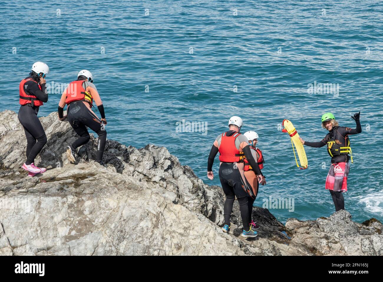 I turisti e la loro guida inizieranno un'avventura in coastering a Towan Head a Newquay in Cornovaglia. Foto Stock