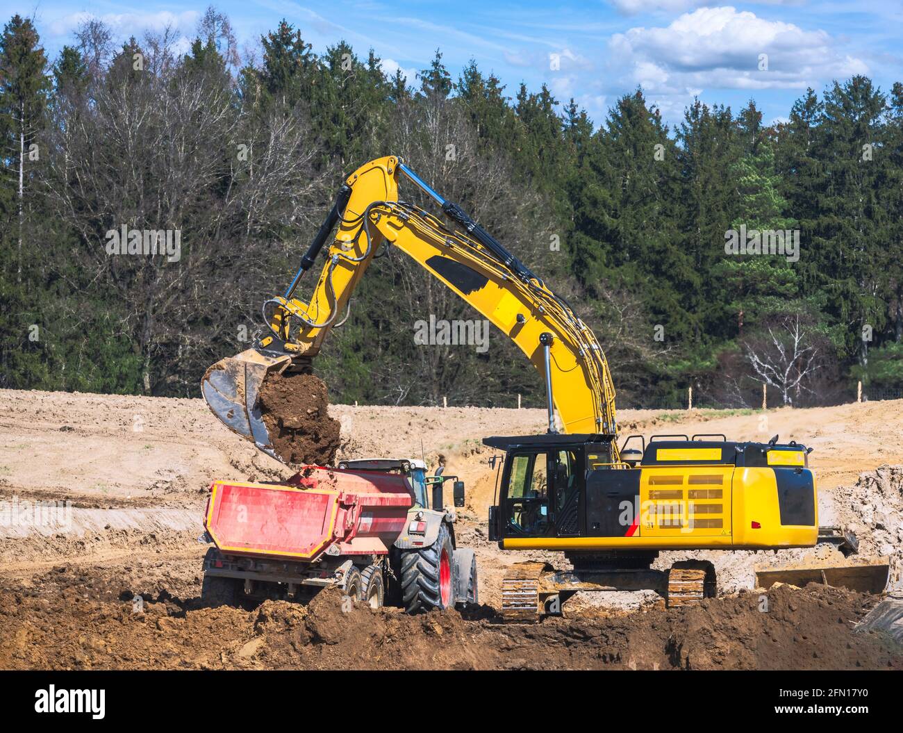 Falda terra gialla che riempie un autocarro in un cantiere Foto Stock