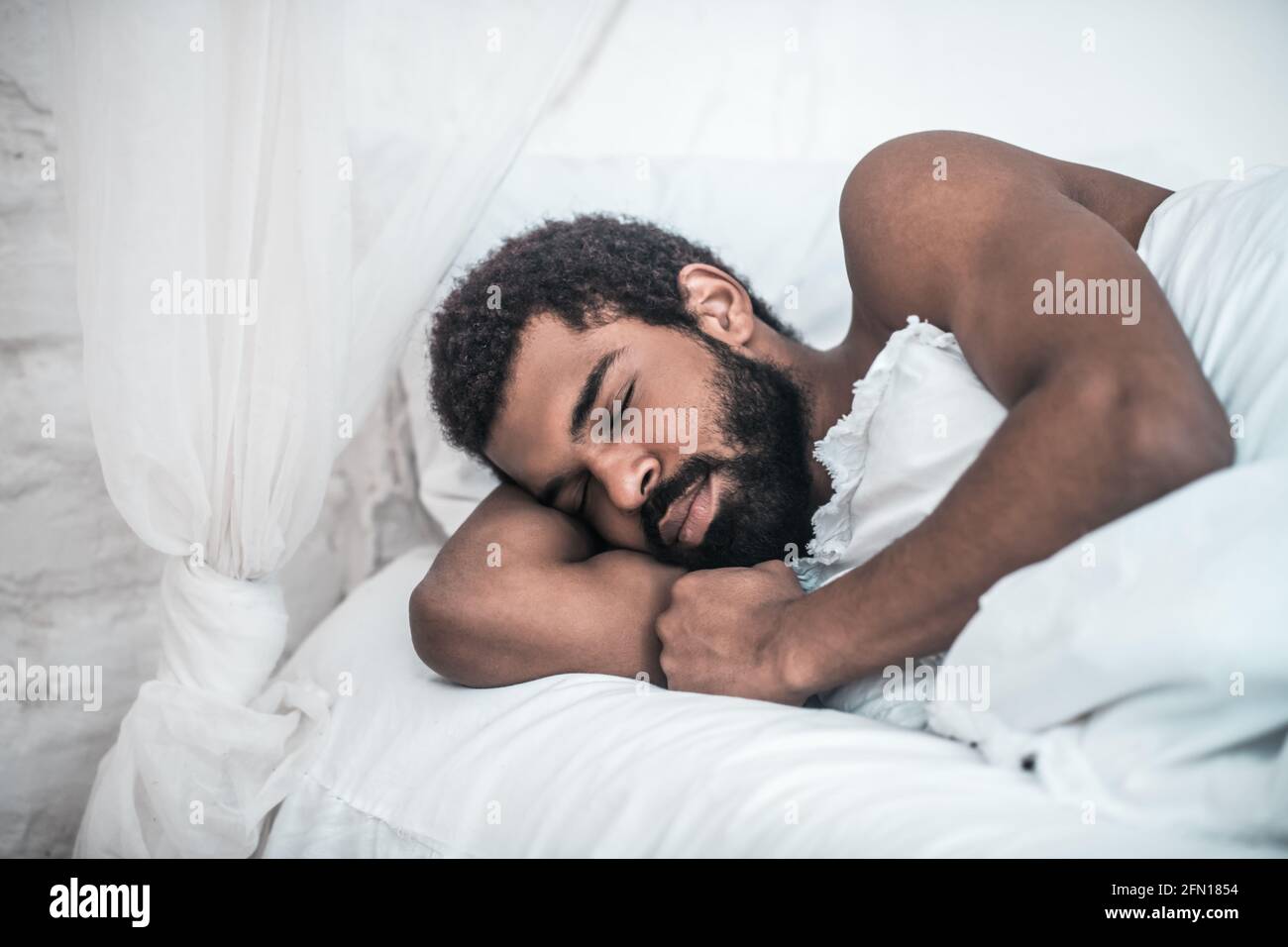 Suono afroamericano addormentato nel letto bianco Foto Stock