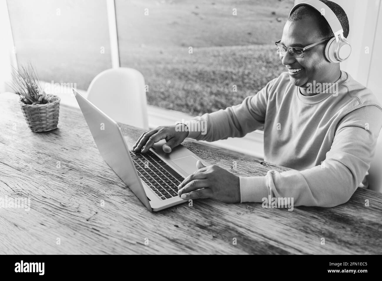 Uomo africano anziano che usa il computer portatile mentre indossa le cuffie a. home - Focus sul viso Foto Stock