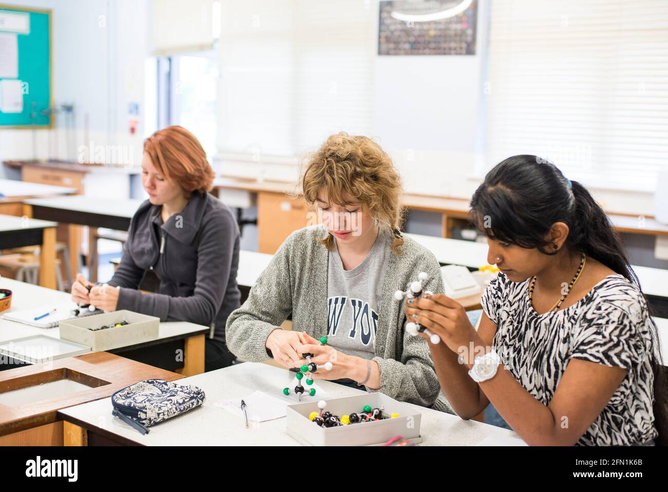 Sesta forma studenti, giovani in istruzione, due adolescenti che collaborano, 3 giovani donne che lavorano con il kit modello molekolare in chimica Foto Stock