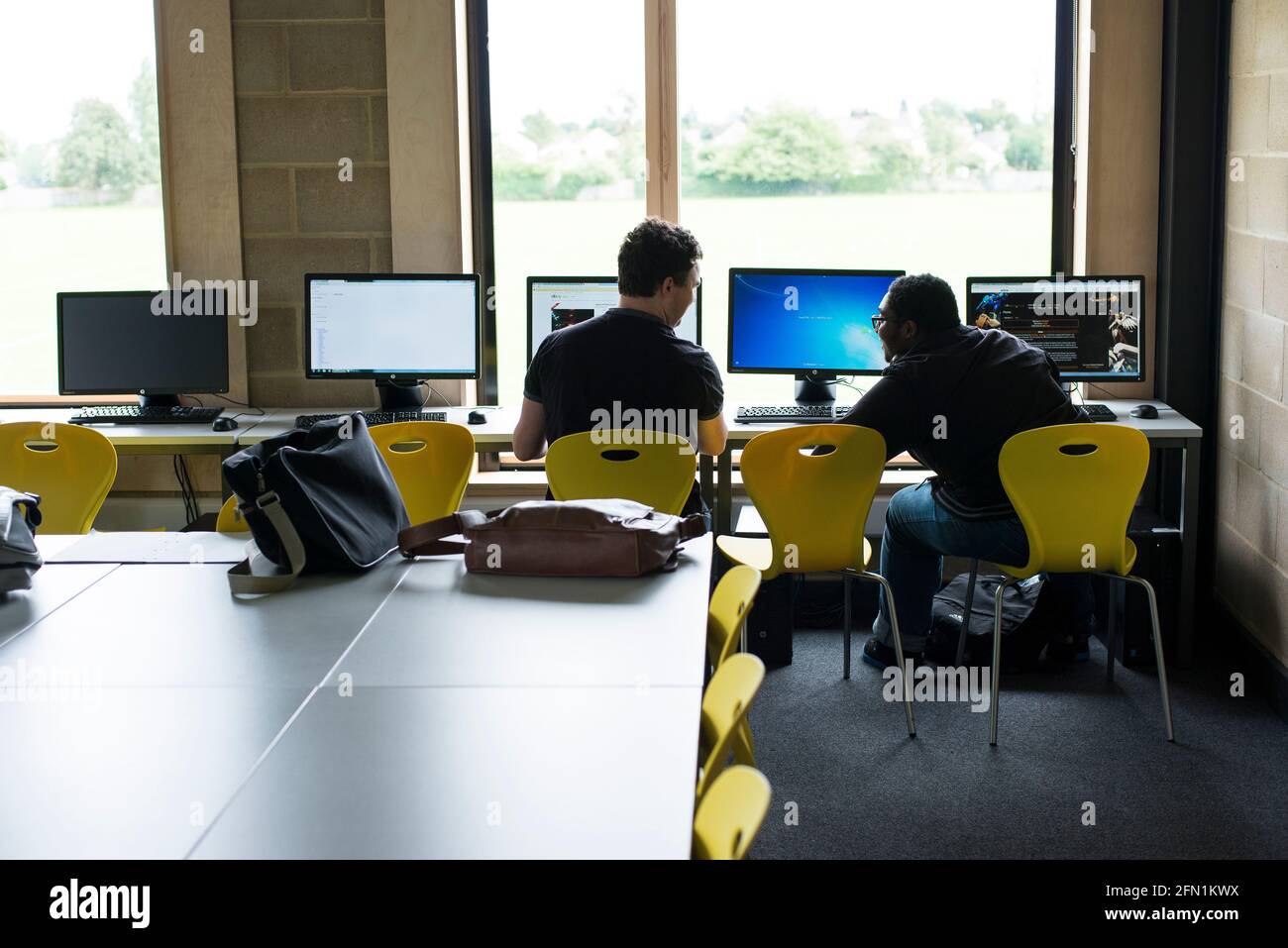 Sesta forma di studenti, giovani in istruzione, due adolescenti che collaborano agli schermi, 2 giovani maschi in sesta forma che lavorano insieme Foto Stock