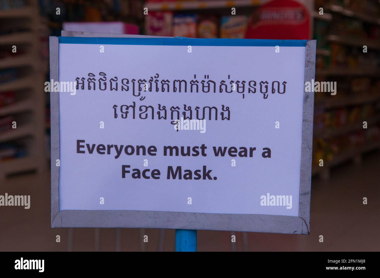 Durante un'epidemia di COVID - 19, un supermercato mostra un cartello bilingue "tutti devono indossare una maschera facciale" durante la pandemia del coronavirus. Phnom Penh, Cambogia. 29 Marzo 2020. © Kraig Lieb Foto Stock