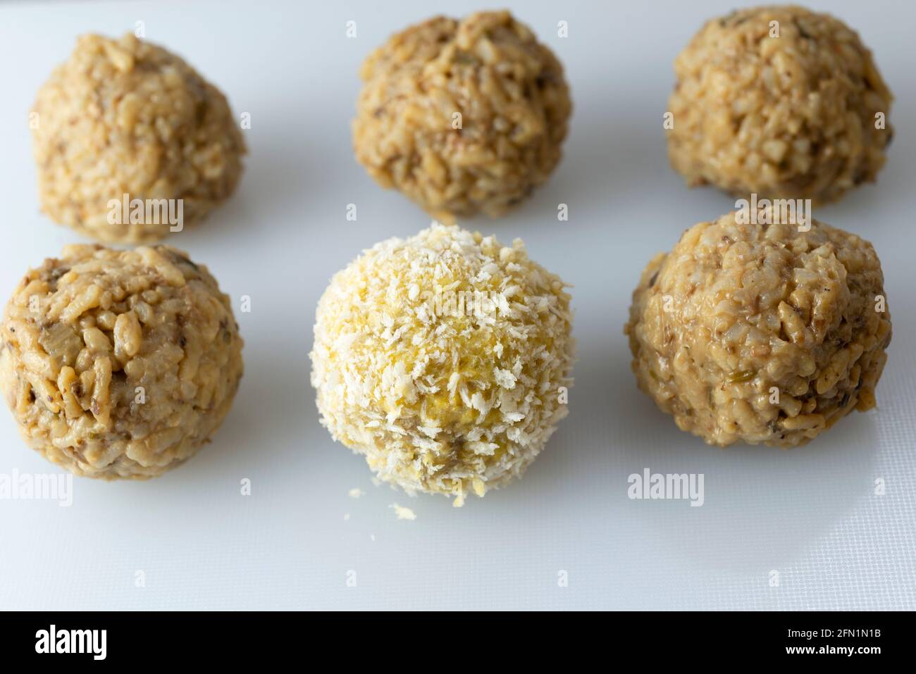 Fare arancini - rivestire le palle di riso in pangrattato. Foto Stock