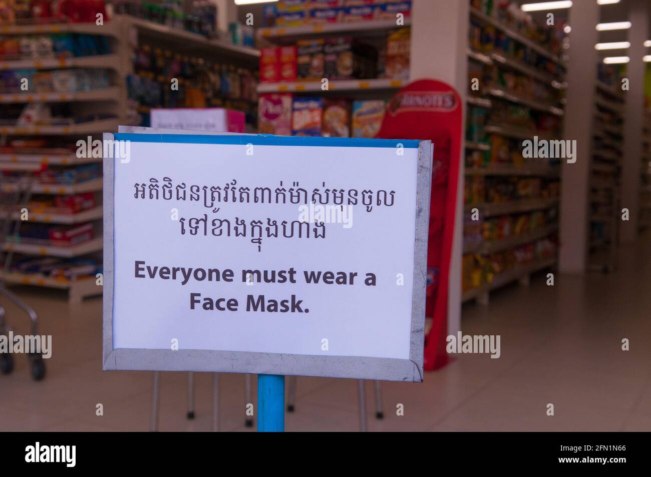 Durante un'epidemia di COVID - 19, un supermercato mostra un cartello bilingue "tutti devono indossare una maschera facciale" durante la pandemia del coronavirus. Phnom Penh, Cambogia. 29 Marzo 2020. © Kraig Lieb Foto Stock