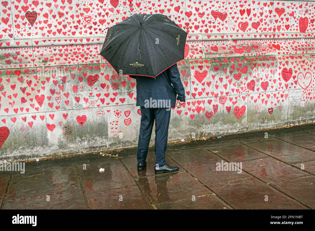 WESTMINSTER LONDRA 13 maggio 2021. Un pedone con un ombrello si affaccia sul muro dei cuori al National Covid Memorial Wall lungo l'argine del Tamigi dedicato alle famiglie in lutto per Justice UK. Il primo ministro Boris Johnson ha annunciato di tenere un’indagine pubblica indipendente che si terrà nel 2022 sulla gestione da parte del governo della pandemia del coronavirus che ha causato 150,000 vittime e di nominare un presidente e dei panelisti. Credit amer Ghazzal/Alamy Live News Foto Stock