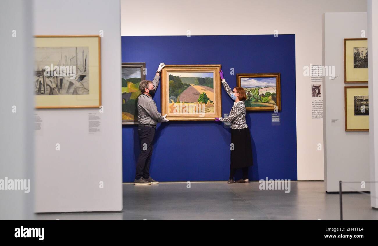 Brighton UK 13 maggio 2021 - Co-curatori Sara Cooper e Andy Friend con il famoso dipinto di Cornfield di John Nash al Towner Eastbourne mentre si preparano a presentare la prima grande mostra di John Nash opere in 50 anni, come gallerie in tutta l'Inghilterra riaprono dopo il blocco. Towner Eastbourne presenta la più completa mostra di opere in oltre 50 anni di John Nash, uno degli artisti più versatili e prolifici del XX secolo. Credit: Simon Dack/Alamy Live News Foto Stock