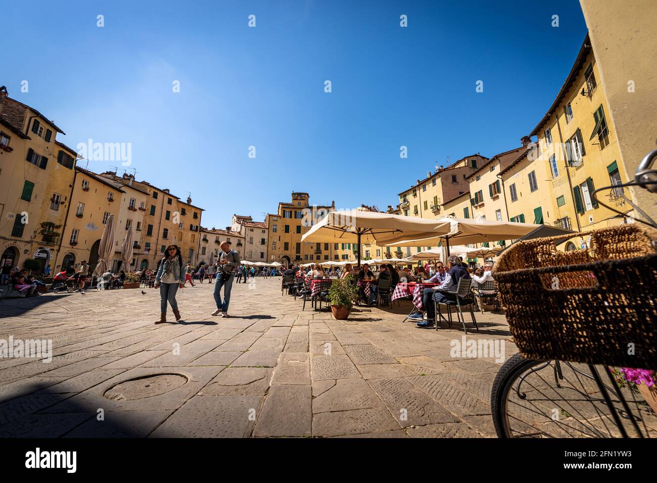 Piazza dell'Anfiteatro nel centro di Lucca. I turisti e la gente del posto visitano l'antica piazza ellittica della città. Toscana, Italia, Europa. Foto Stock