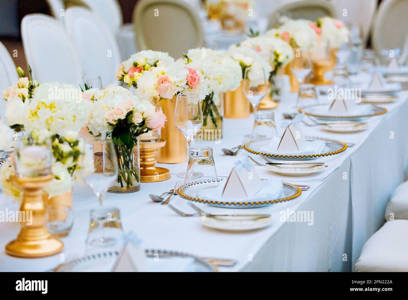 Tavolo matrimonio allestito in oro e bianco. Foto Stock